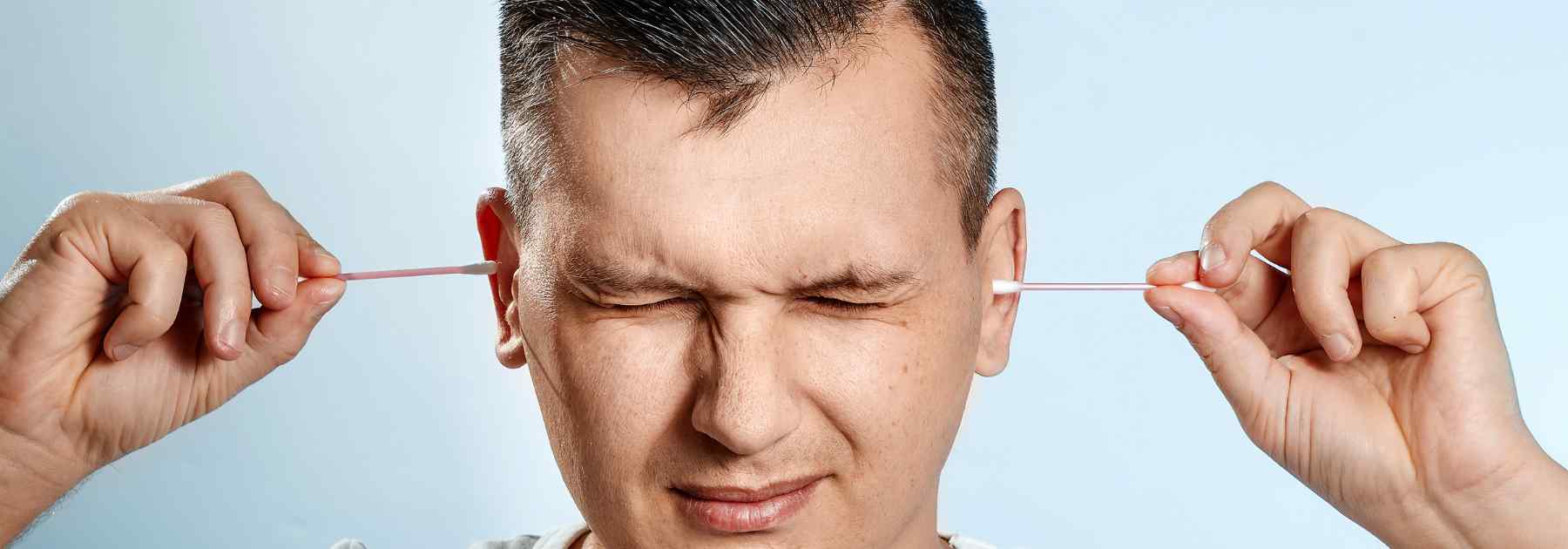 Man making his ears sore and blocked using cotton buds